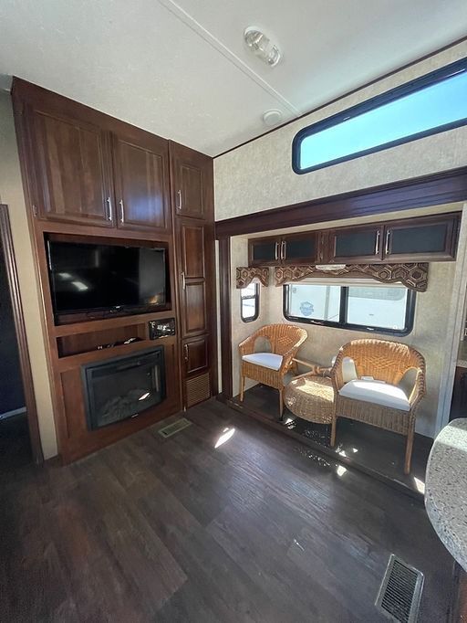 A living room with two chairs , a fireplace and a flat screen tv.