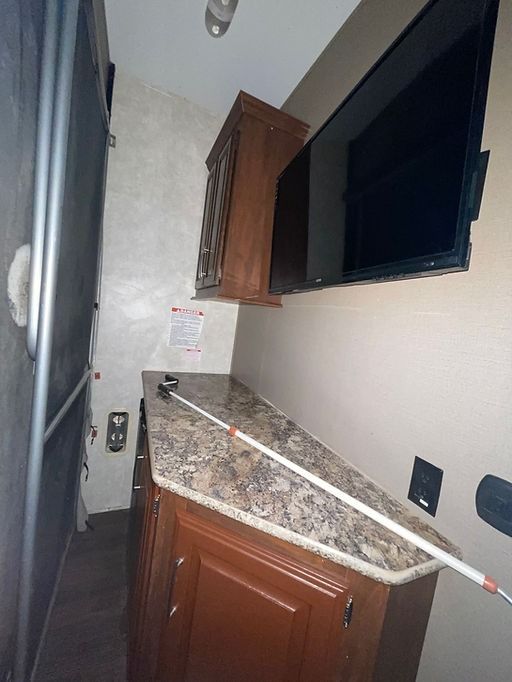 A kitchen with a large flat screen tv on the wall above the counter.