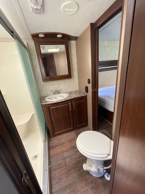 A bathroom with a toilet , sink and mirror.