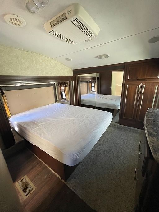 A bedroom in a rv with a king size bed and two mirrors.