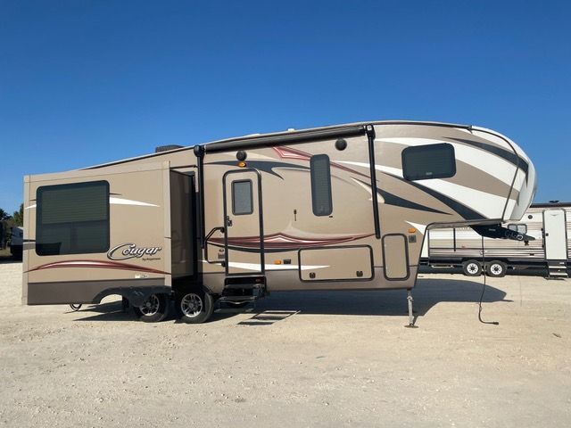 A brown and white rv is parked in a gravel lot.
