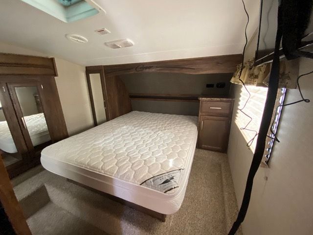 A bedroom in a trailer with a bed and a window.