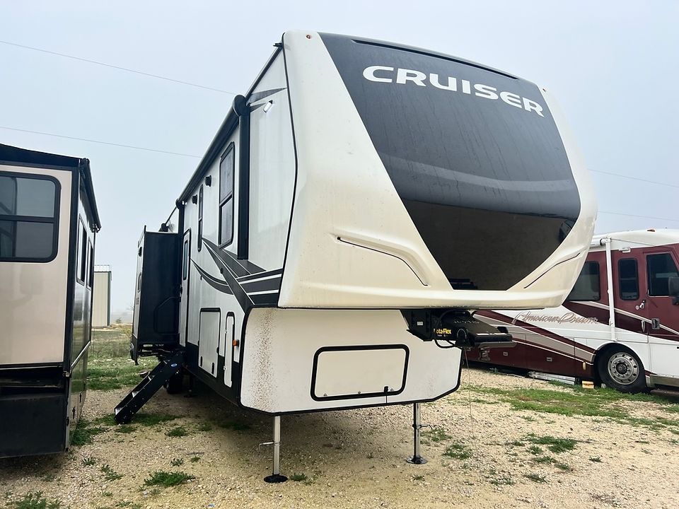 A white and black rv is parked in a dirt lot next to another rv.
