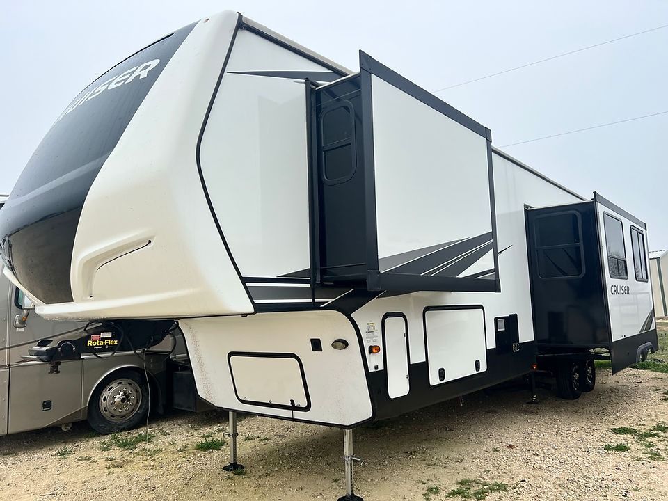 A white and black trailer is parked in a gravel lot.