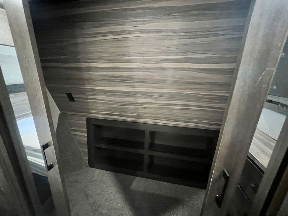 A closet with a wooden wall and a shelf in it.