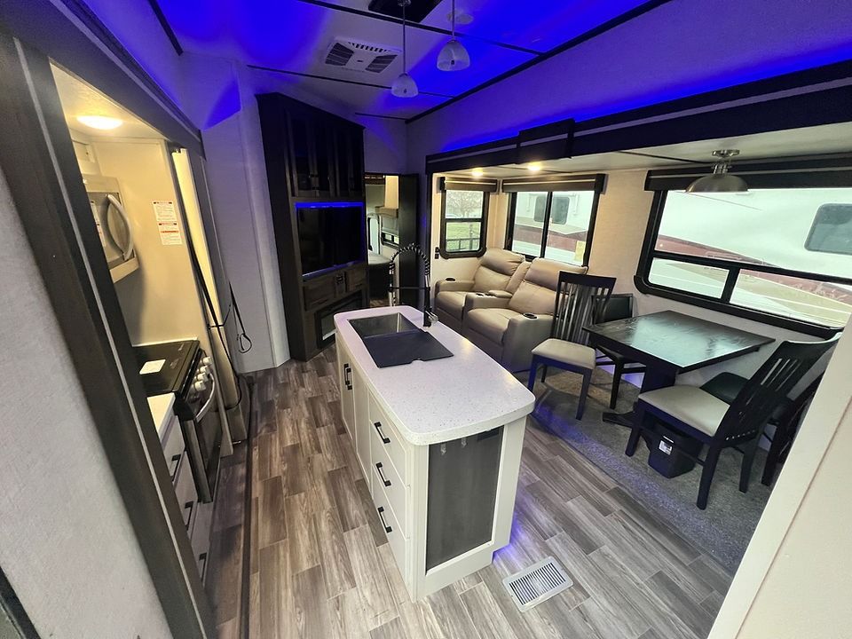A rv with a kitchen , dining room , and living room.