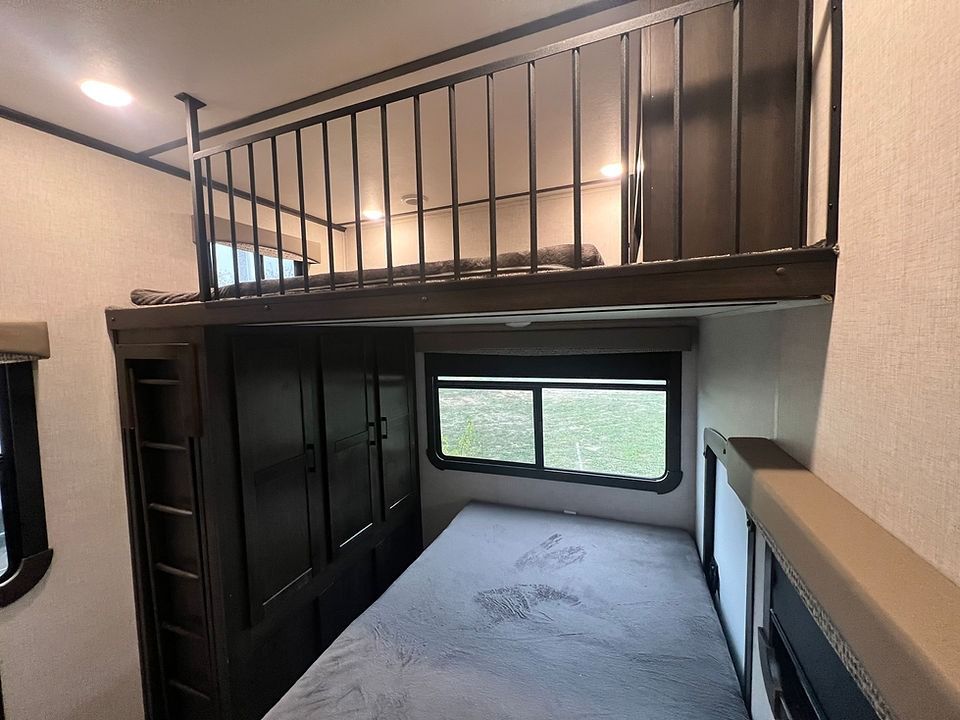 A bedroom with a bunk bed and a balcony above it.
