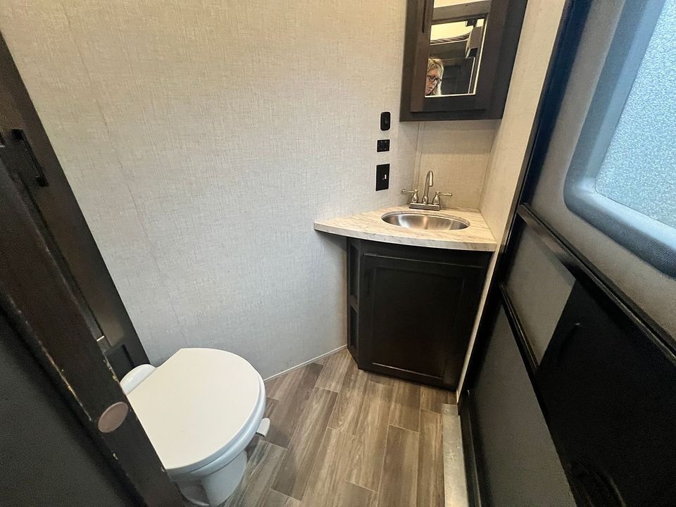 A bathroom with a toilet , sink and mirror.