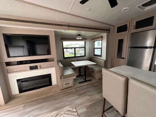 A living room with a fireplace , television , table and chairs.