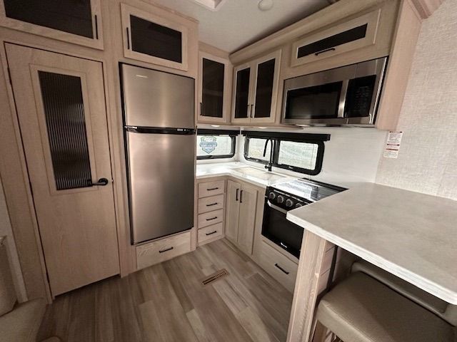A kitchen in a rv with stainless steel appliances and wooden cabinets.