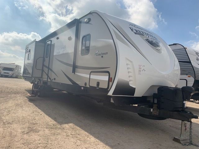 A white rv is parked in a dirt lot.