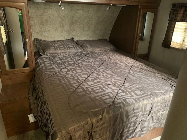 A bedroom in a trailer with a bed and two mirrors.