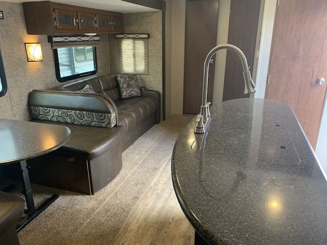 The inside of a rv with a couch , table and sink.