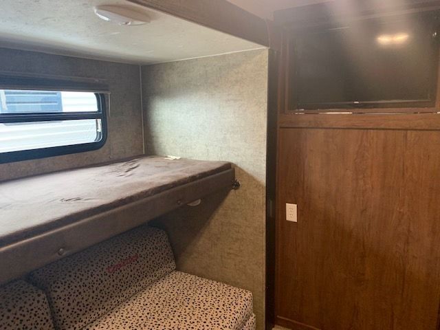 A rv with a bunk bed , couch , and television.