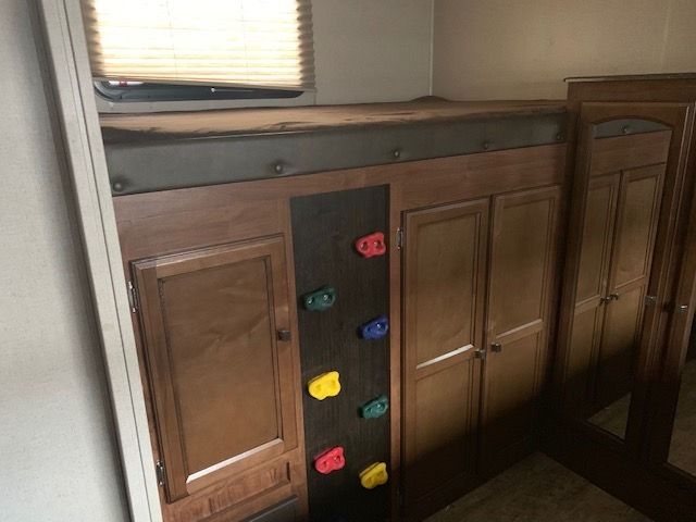 A bedroom with a bunk bed and a climbing wall