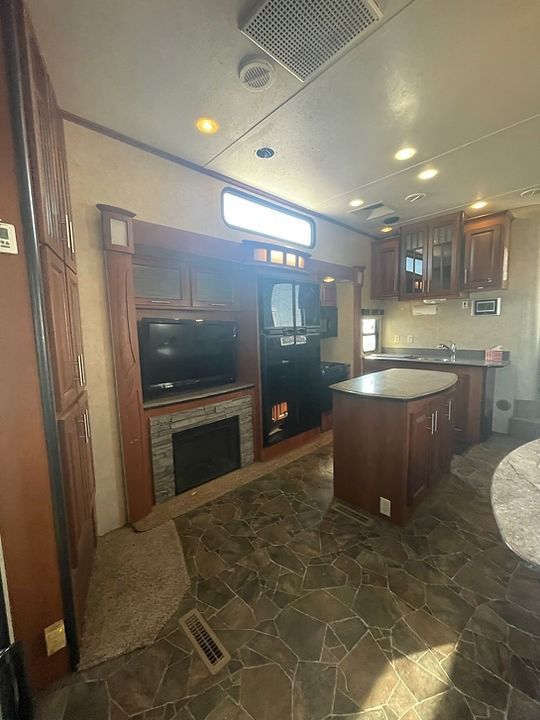 A living room with a fireplace , television , refrigerator and microwave.