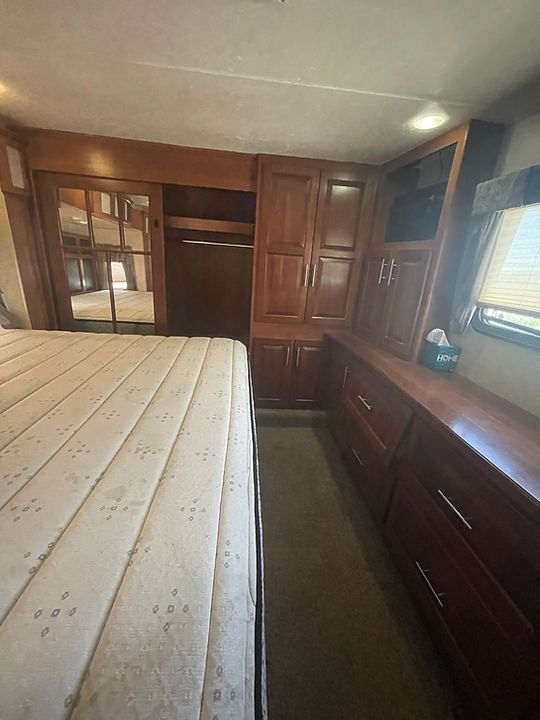 A bedroom with a bed , cabinets and drawers.