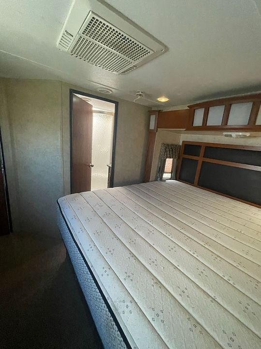 A bedroom with a mattress and a door leading to a bathroom.