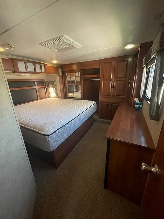 A bedroom in a rv with a king size bed and a desk.