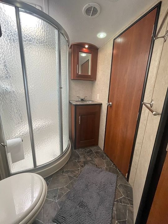 A bathroom with a toilet , sink , shower and mirror.