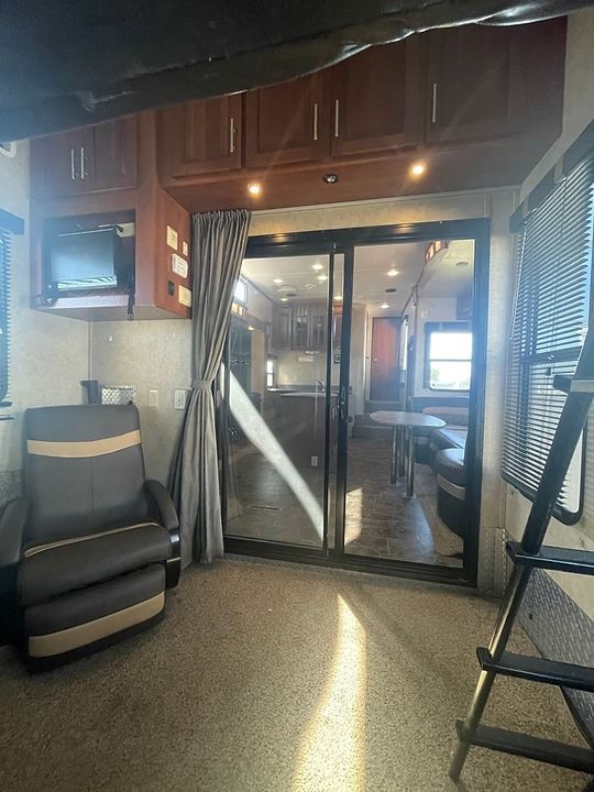 A living room with a chair , ladder and sliding glass doors.