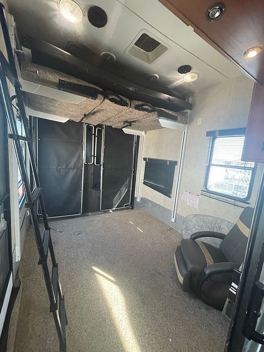 A rv with a bunk bed and a ladder in the ceiling.