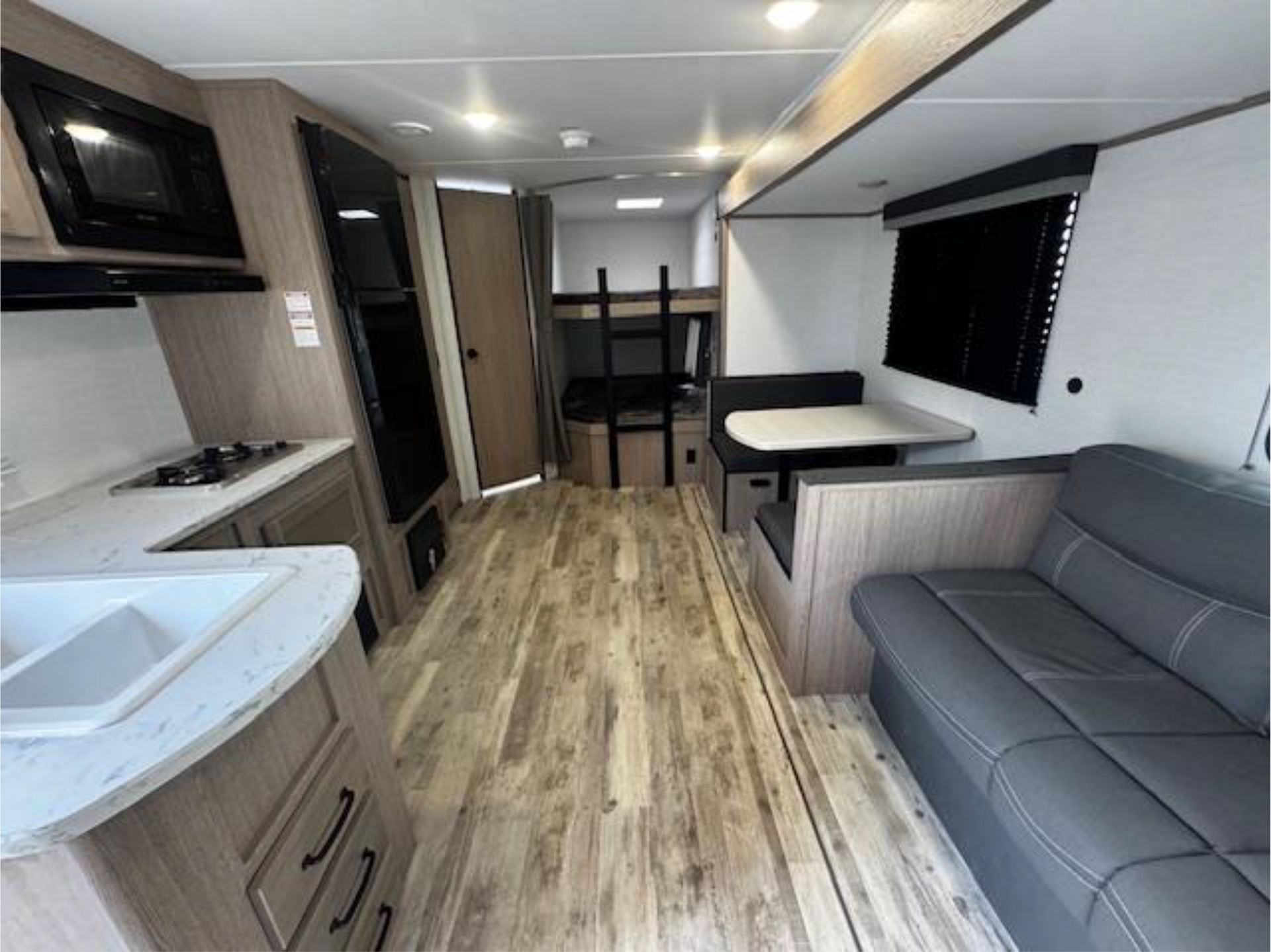 The inside of a RV with a couch, table, and sink
