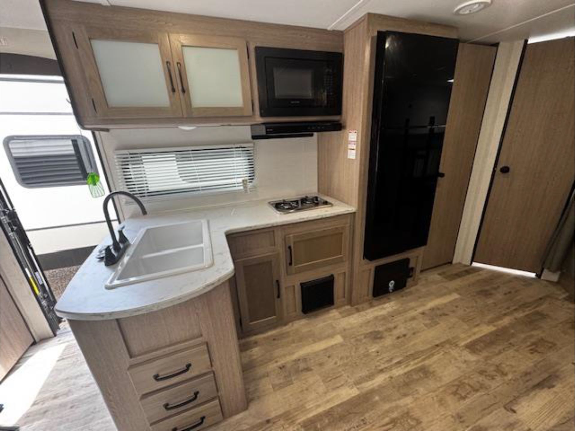 A kitchen in a RV with a sink, stove, refrigerator, and microwave