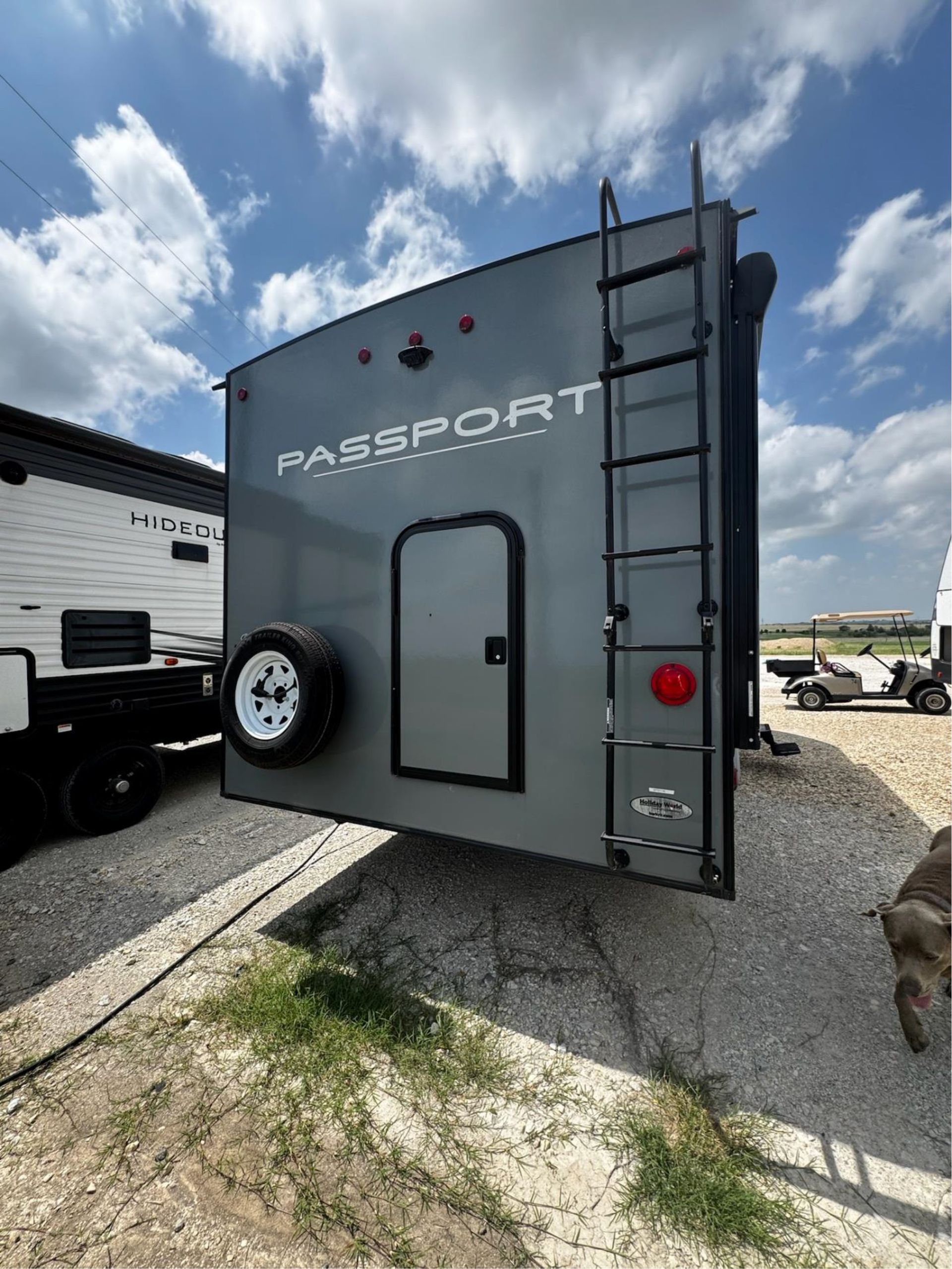 A passport trailer is parked in a gravel lot