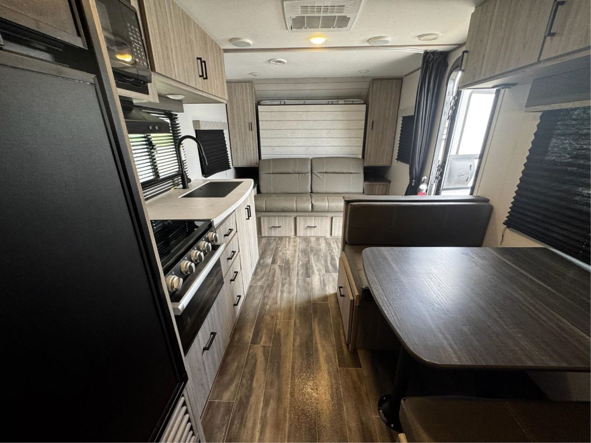 The inside of a RV with a couch, table, and stove