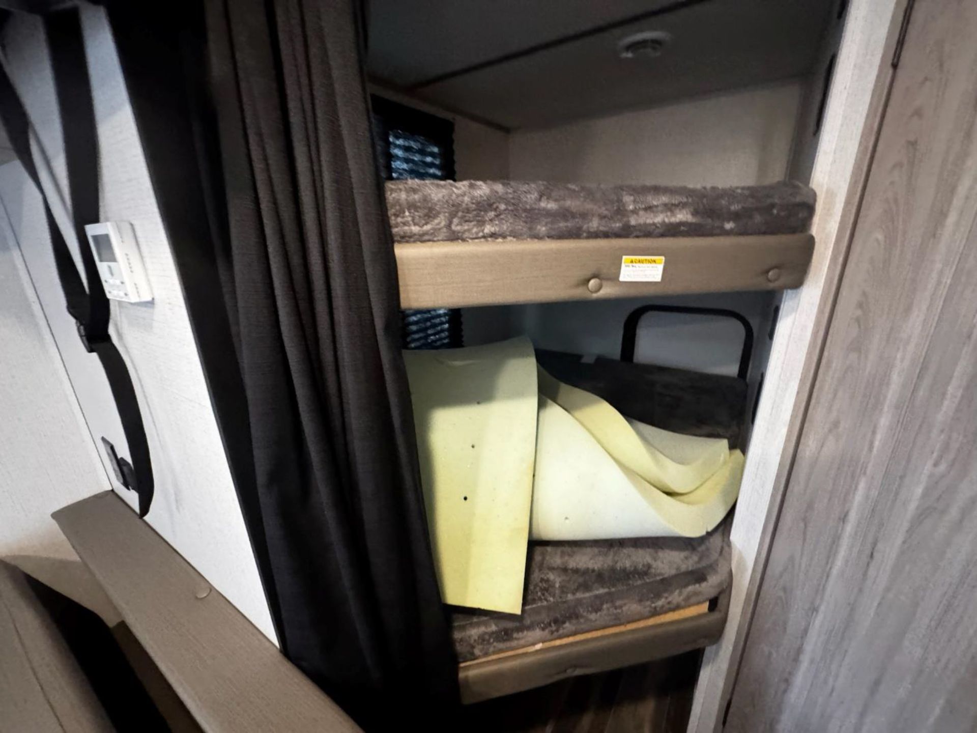 A bunk bed in a closet with a curtain behind it