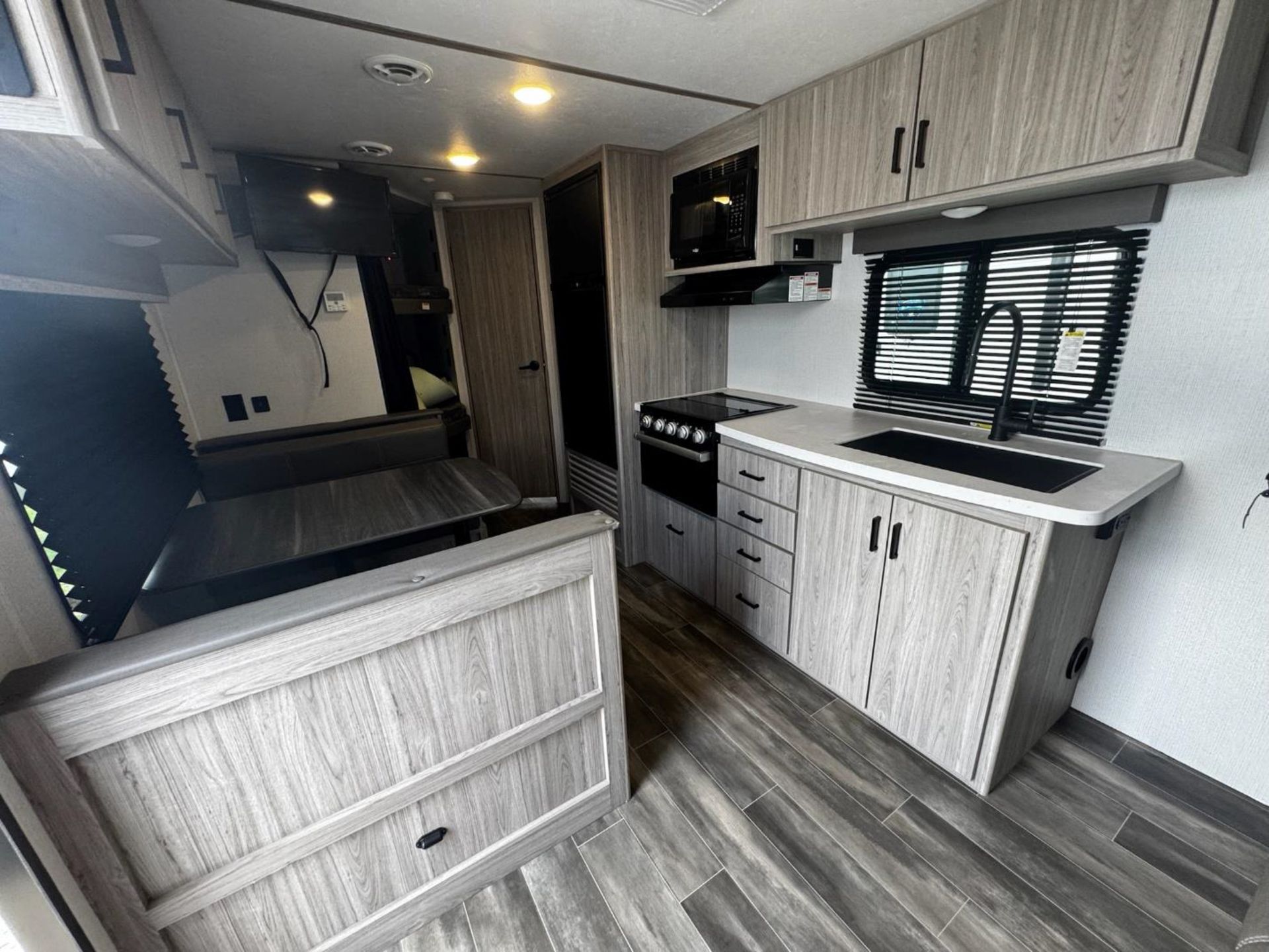 A kitchen in a RV with wooden cabinets, a sink, and a stove