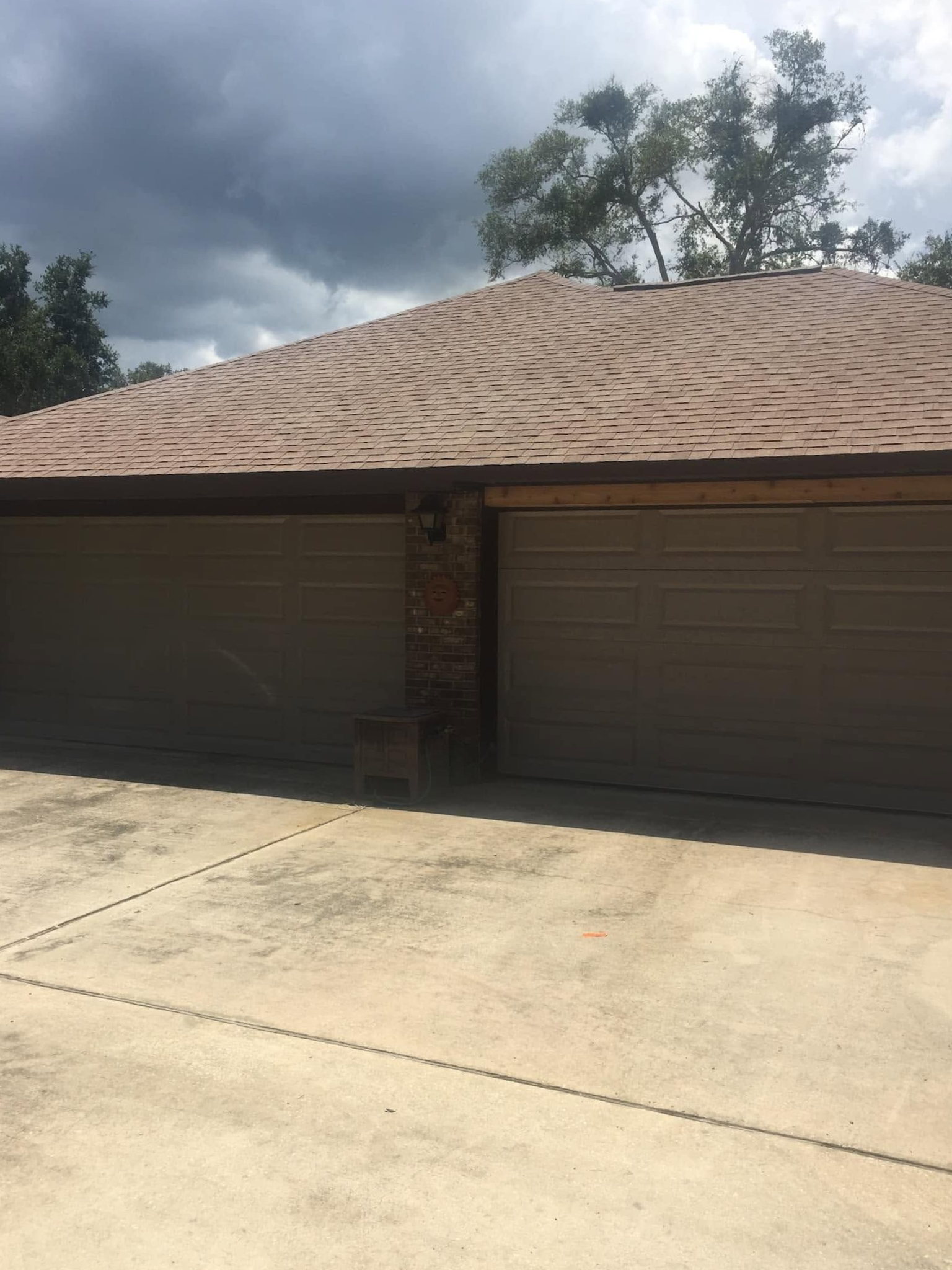 Single-story house with a tan tiled roof and large garage doors under a cloudy sky