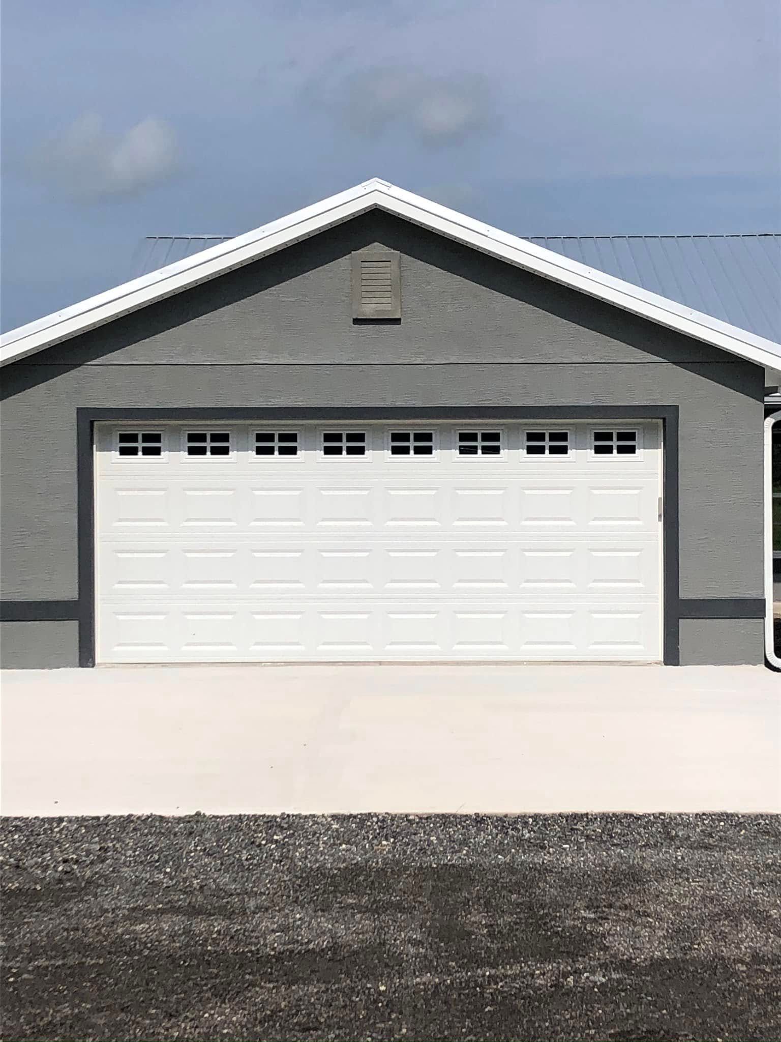 Gray house with a white two-car garage door under a blue sky