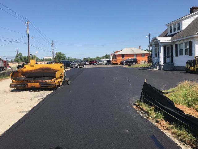 Freshly paved street with construction equipment and houses on a sunny day