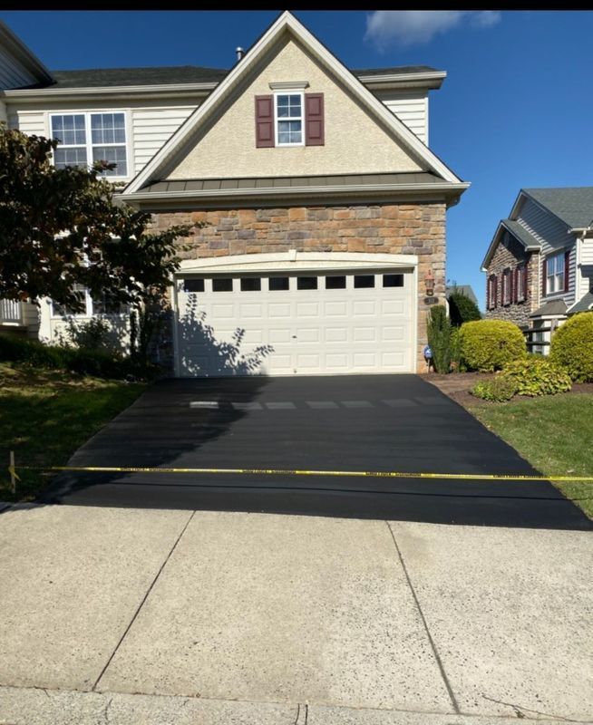 Two-story house with a newly paved black driveway. A yellow caution tape is across the driveway.