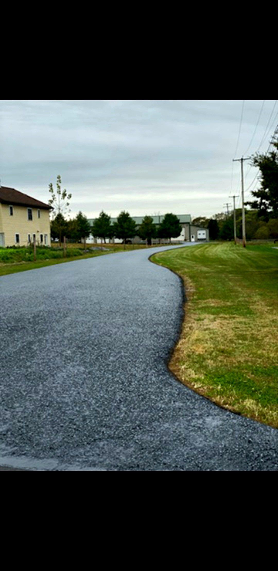 A winding gravel path alongside a grassy area, under a cloudy sky.