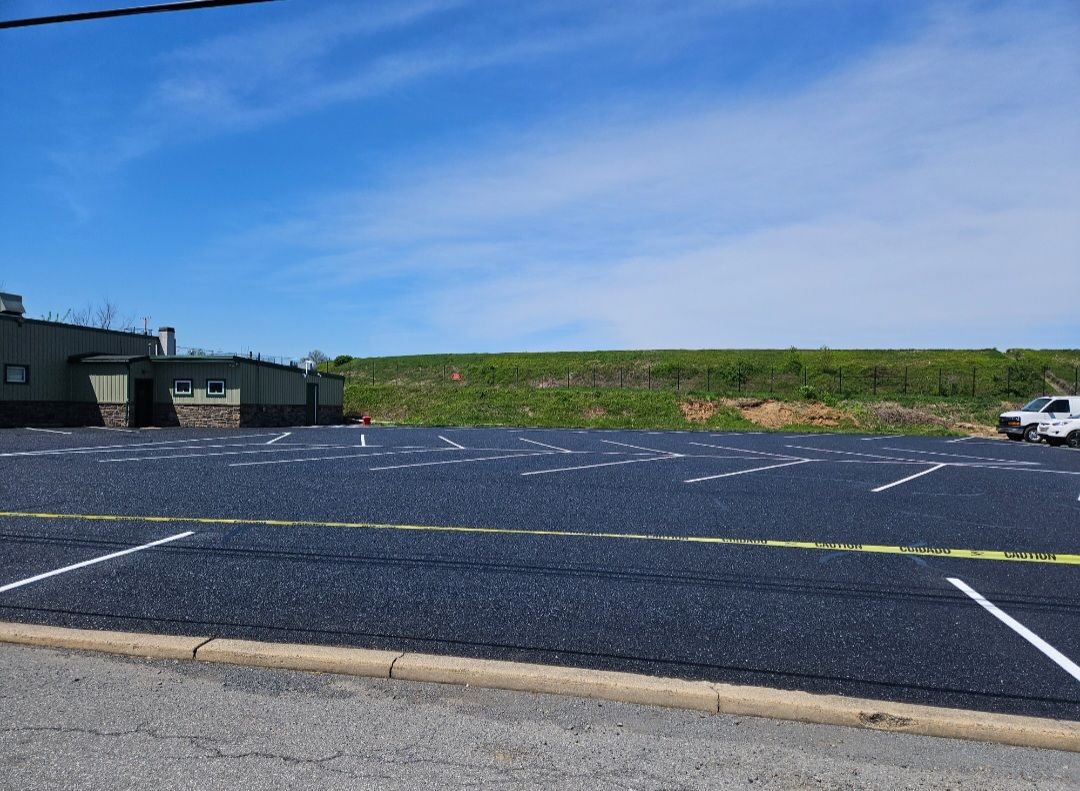 Newly paved parking lot with marked spaces in front of a building under a blue sky.