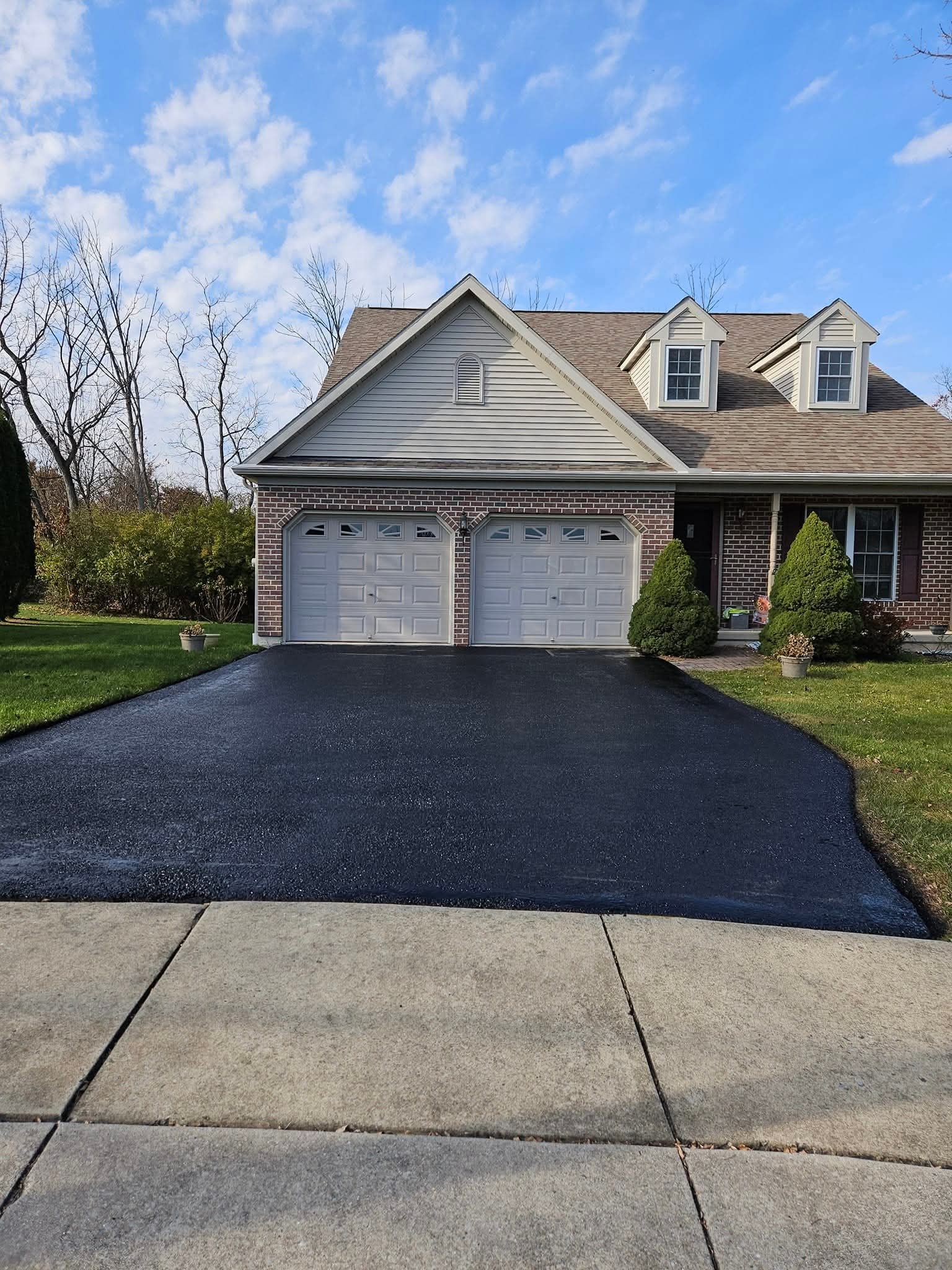 Black asphalt driveway in front of a house with a two-car garage.