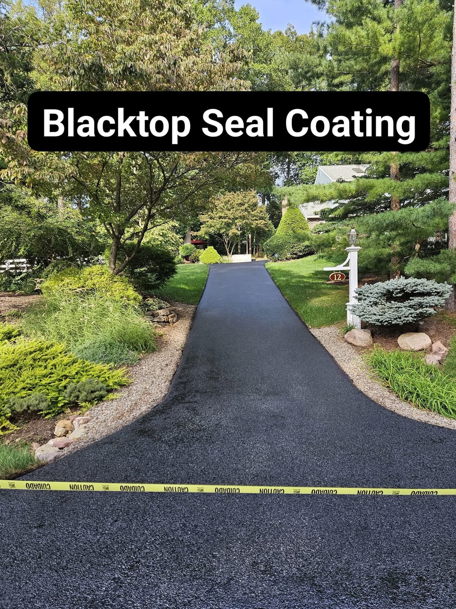 Blacktop driveway with fresh seal coating, flanked by green grass and shrubs. Yellow caution tape in foreground.