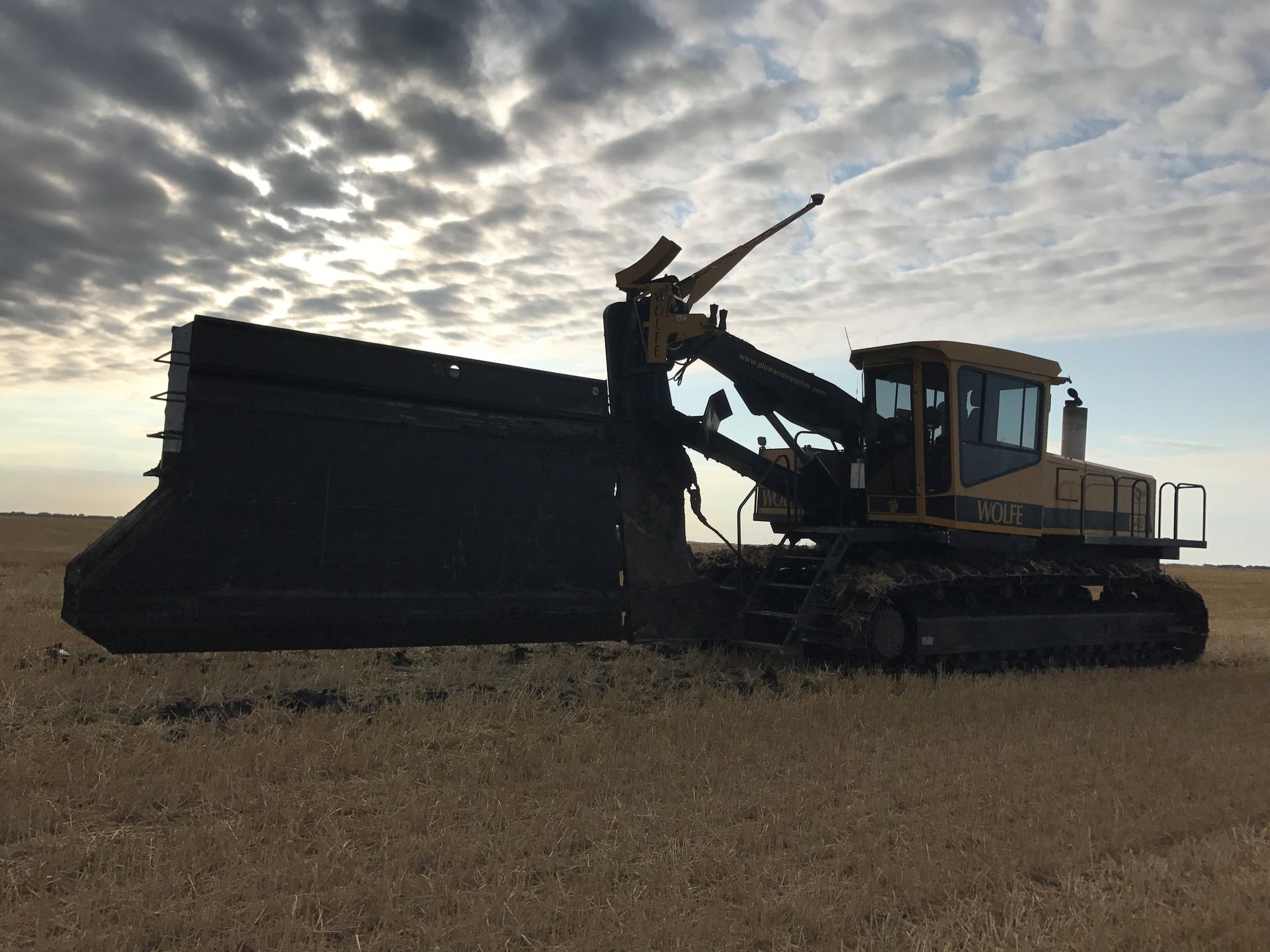 A bulldozer is parked in a field with a cloudy sky in the background