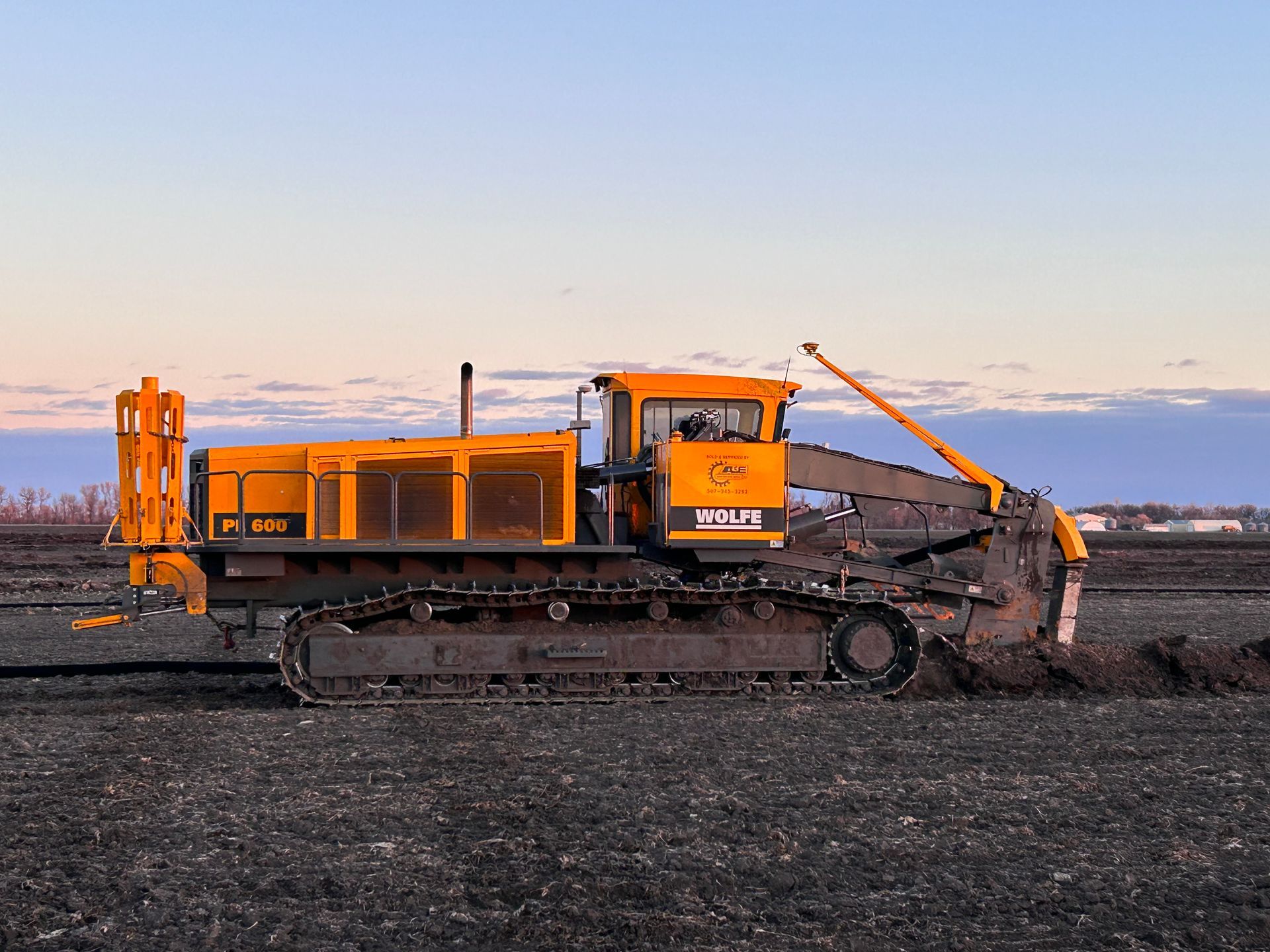 A yellow bulldozer is driving through a dirt field.