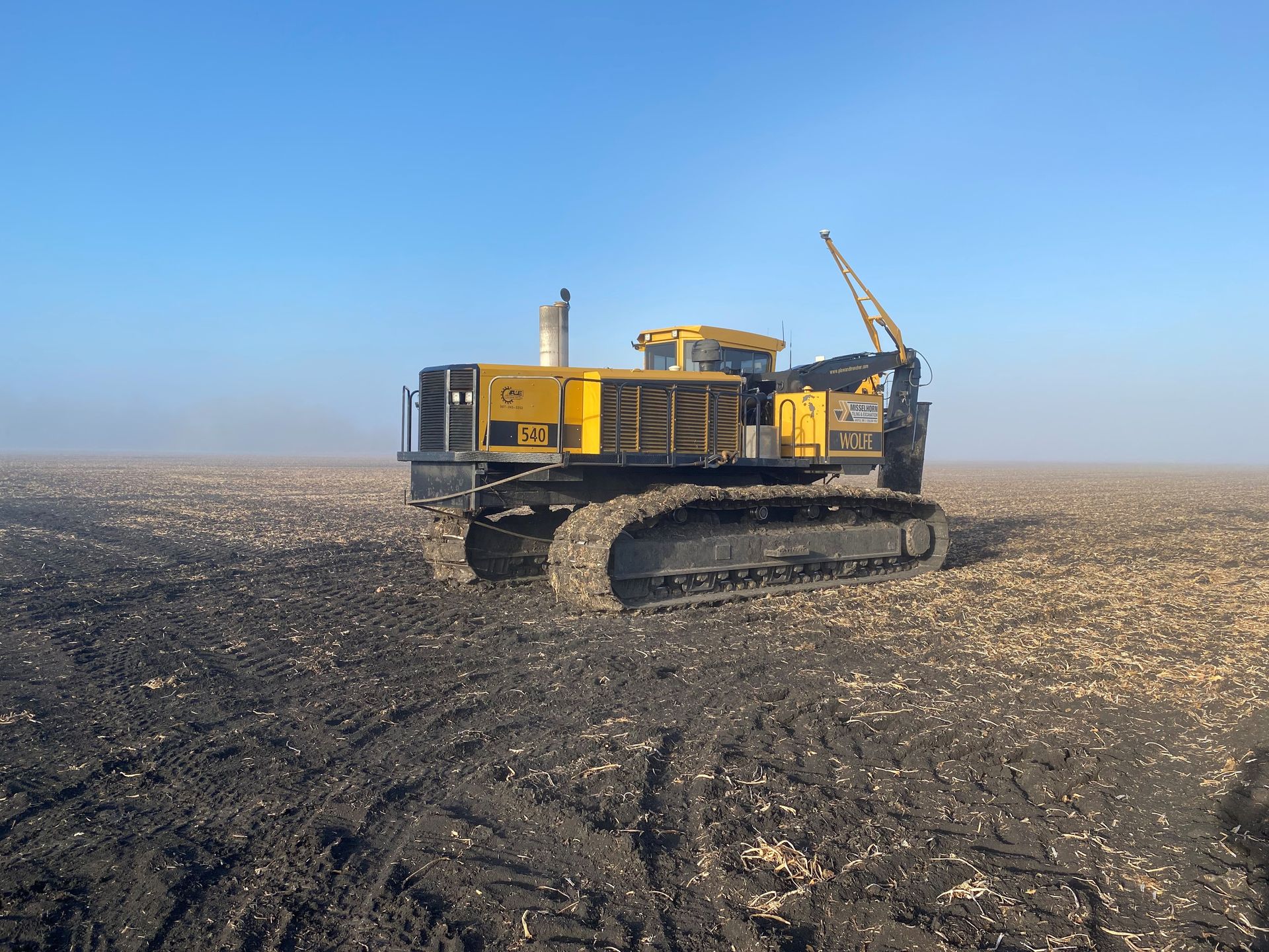 A yellow bulldozer is parked in a dirt field
