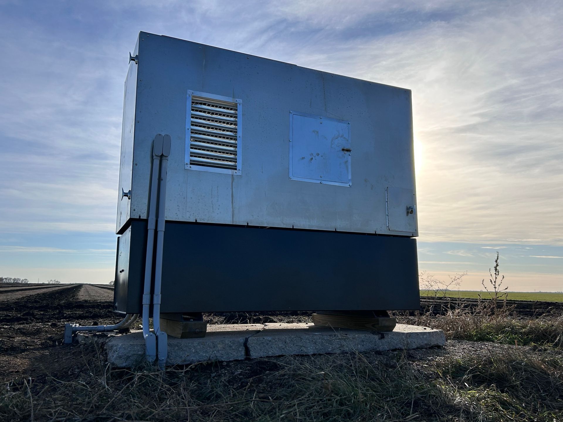 A small building is sitting in the middle of a field.