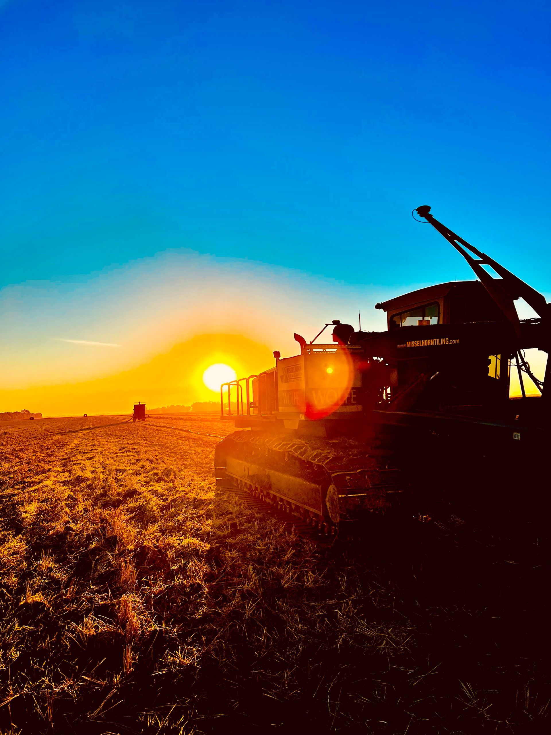 A sunset with a tractor in the foreground