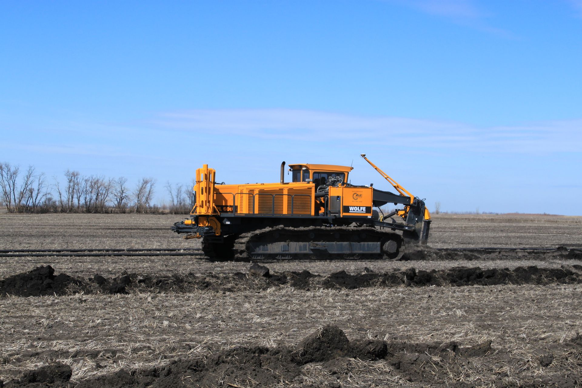 A yellow bulldozer is driving through a dirt field.