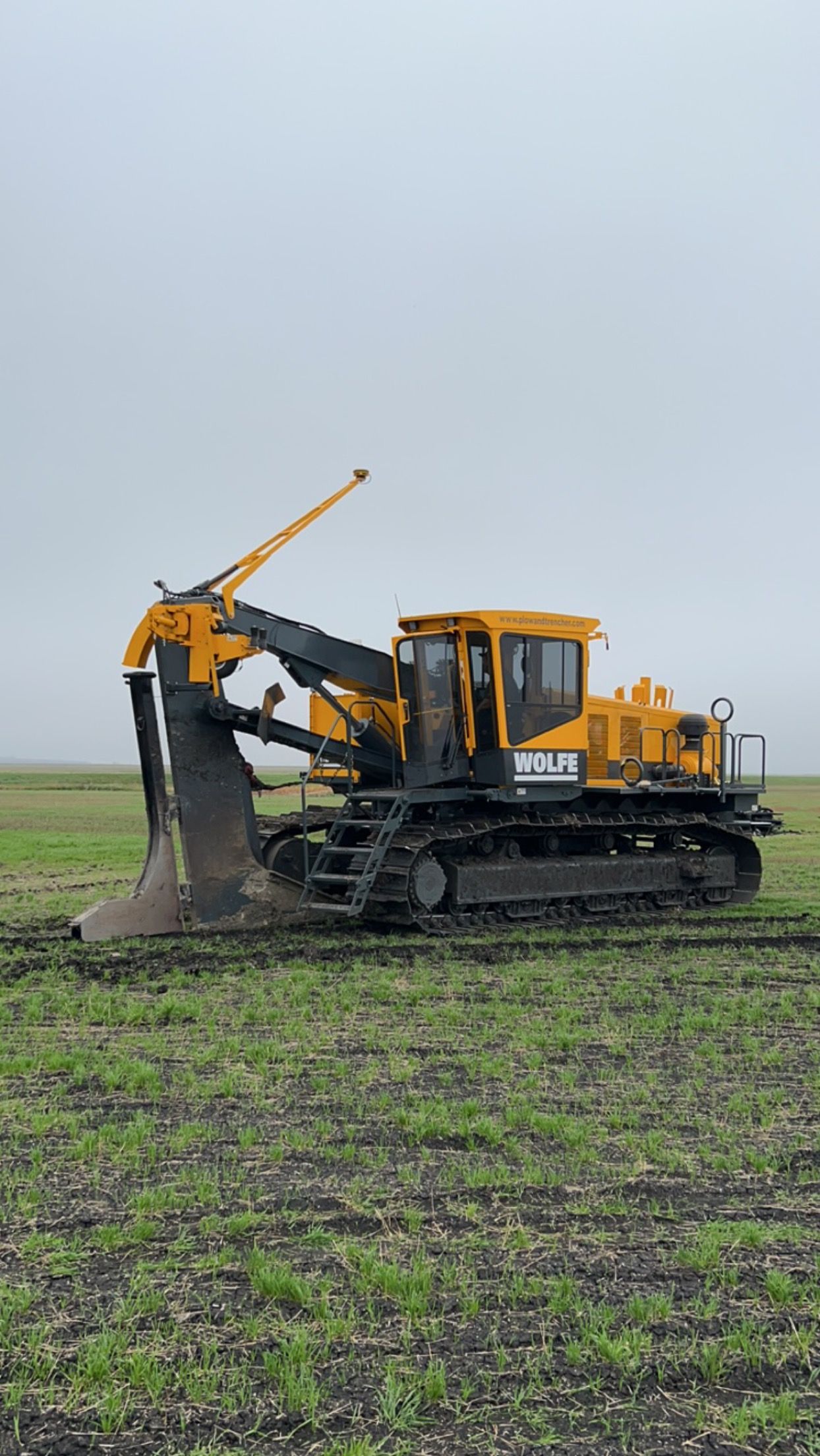 A yellow bulldozer is digging a hole in a field.
