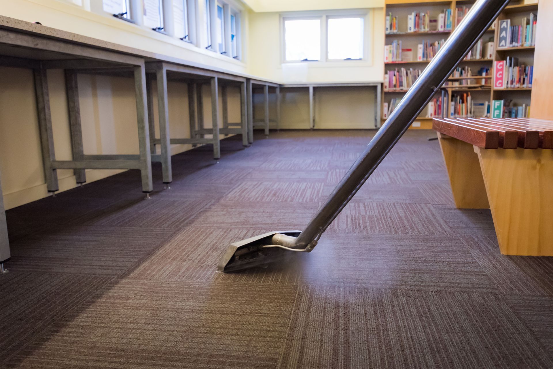 A vacuum cleaner is cleaning the floor of a library.