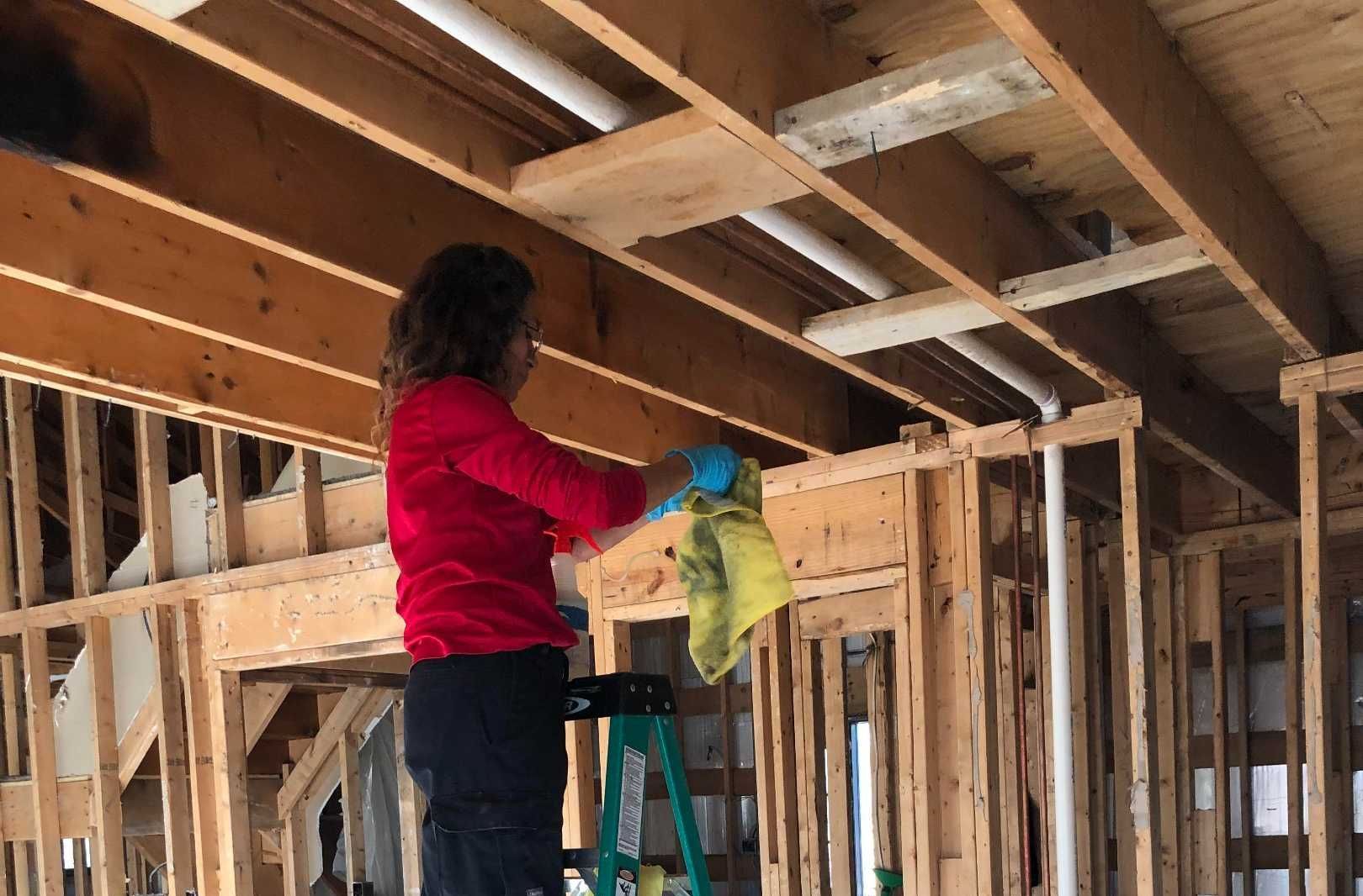 A woman is cleaning the ceiling of a house under construction.