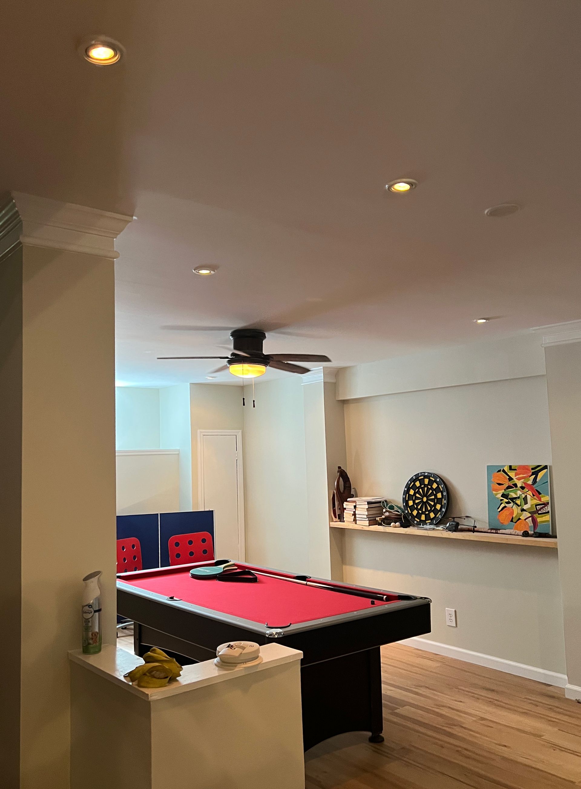 Pool table with red felt in a game room with hardwood floors and recessed lighting.